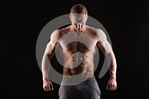 Athletic handsome man fitness-model showing six pack abs. isolated on black background with copyspace