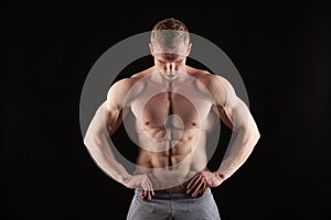 Athletic handsome man fitness-model showing six pack abs. isolated on black background with copyspace