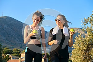 Athletic healthy family lifestyle, happy mother and teenage daughter eating apples