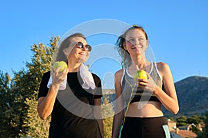 Athletic healthy family lifestyle, happy mother and teenage daughter eating apples