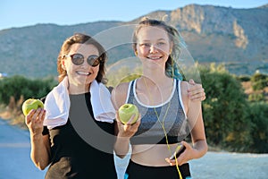 Athletic healthy family lifestyle, happy mother and teenage daughter eating apples