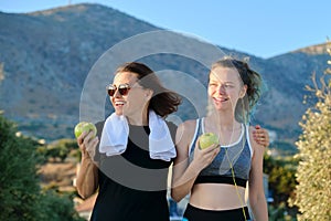 Athletic healthy family lifestyle, happy mother and teenage daughter eating apples