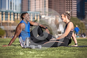 Athletic and healthy fitness partners, friends, male and female exercise group casual in the city park lawn, relaxing and laughing