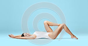 Athletic and healthy girl posing in white bodysuit. Fit and woman in underwear swimsuit. Slim shape, nutrition