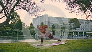 Athletic lady performing yoga pose at park. Woman extended side angle position