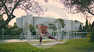 Athletic lady performing yoga pose at park. Woman extended side angle position