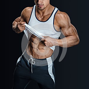 Athletic male model posing, pulling up tank top