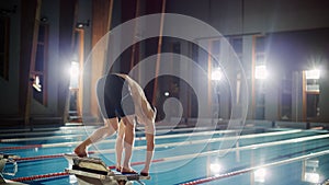 Athletic Male Swimmer Stands on a Starting Block, Ready to Dive into Swimming Pool. Determined