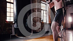 An athletic man boxer training with a punching bag in the gym