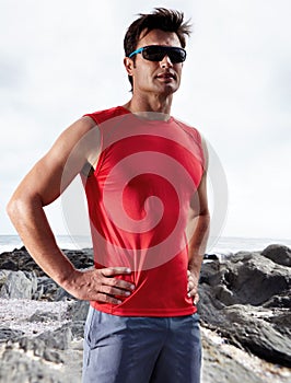 Athletic man, confident and beach for fitness, health and wellness in activewear and sunglasses. Male person, jog and