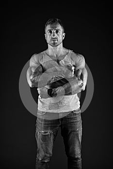 Athletic man cross strong muscular arms with biceps triceps muscles in casual wear black background, sportsman