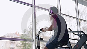 Athletic man doing intense workout on air bike in modern gym