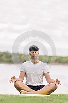 Athletic man doing the lotus position of yoga outdoors