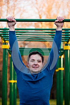 Athletic man doing pull-up on horizontal bar