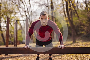 Athletic man doing push ups while exercising in street workout park