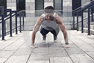 Athletic man doing push ups, urban workout concept