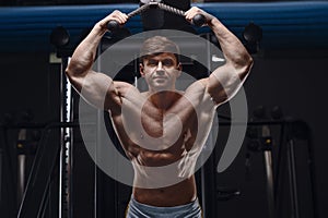 Athletic man exercising pumping up triceps muscles
