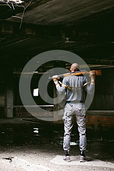 Athletic man in gray clothes with a carbine gun in his hand