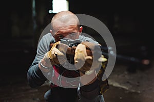 Athletic man in gray clothes with a carbine gun in his hand