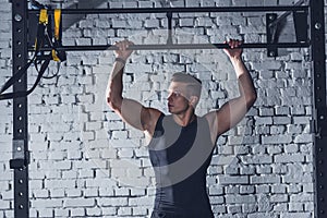 athletic man with hands on pull up bar looking away