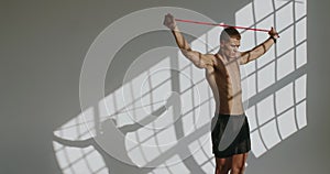 Athletic man has workout and exercising with resistance band on white background