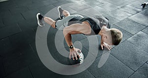 Athletic man has workout at gym and doing push up exercises with medicine ball