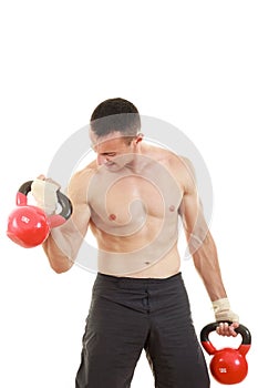 Athletic man holding and lifting up red kettlebells weights one