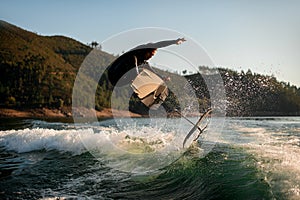 athletic man jump with foil wakeboard over splashing wave