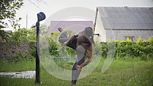 Athletic man with long black hair and a beautiful torso, practic karate in the garden, practicing kicks