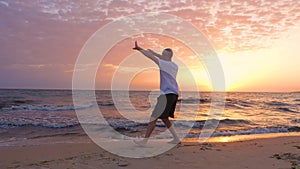 Athletic man practicing Tai Chi asian martial arts on sea beach in the morning