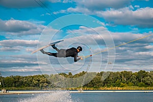 Athletic man practicing wakeboard tricks in training wake park on summer day