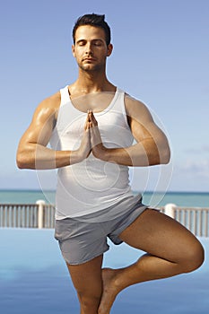 Athletic man practicing yoga outdoors