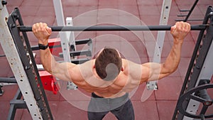 Athletic Man Pumps Up Muscles Doing Pull-Ups Open Sports Ground with Bare Torso