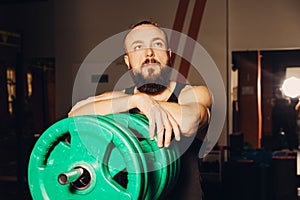 Athletic man puts on plate for barbell in the gym