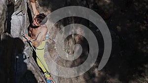 Athletic man rock climber climbs on a cliff, reaching and gripping hold.
