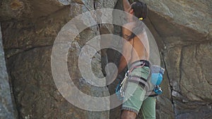 Athletic man rock climber climbs on a cliff, reaching and gripping hold.