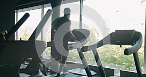 Athletic man run on treadmill at modern gym