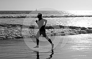 athletic man runner silhouette run on summer beach with sea water and sun, motivation