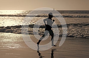 athletic man runner silhouette run on summer beach with sea water and sun, motivation