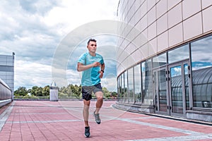 Athletic man running in jump in training, runner in sportswear, training in city during summer, active lifestyle, modern