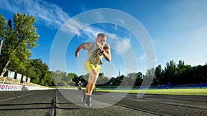 Athletic man running sprint on racetrack