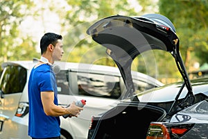 Athletic man in sport outfit standing near her car while going to the gym. Fitness lifestyle concept
