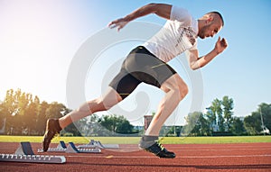 Athletic man on track starting to run. Healthy fitness concept with active lifestyle.