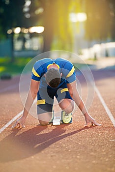 Athletic man on track starting to run. Healthy fitness concept with active lifestyle.