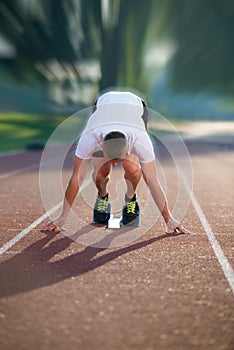 Athletic man on track starting to run. Healthy fitness concept with active lifestyle.