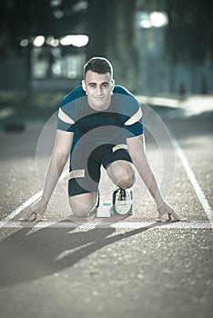 Athletic man on track starting to run. Healthy fitness concept with active lifestyle.