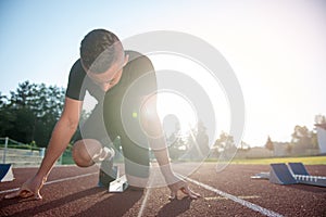 Athletic man on track starting to run. Healthy fitness concept with active lifestyle.