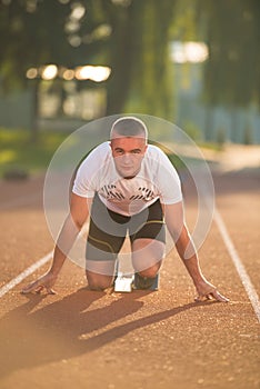 Athletic man on track starting to run. Healthy fitness concept with active lifestyle.