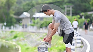 Athletic man tying shoelaces before running, getting ready for jogging outdoors. Healthy lifestyle, workout and wellness