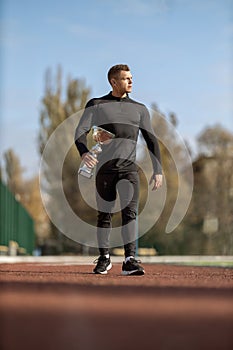 Athletic man walking through the stadium with victory cup